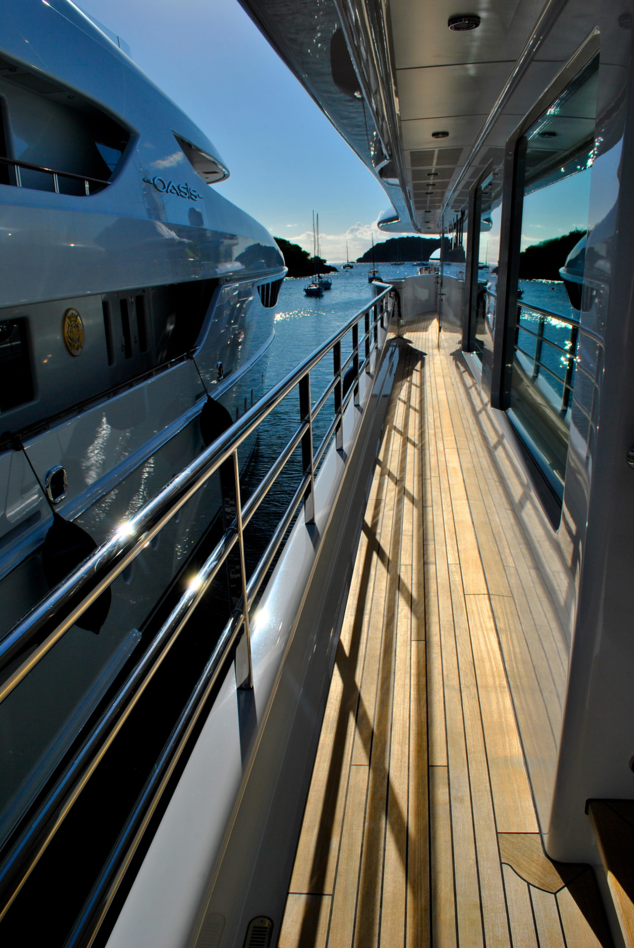 Sunlit teak deck between yachts in a Mediterranean harbour